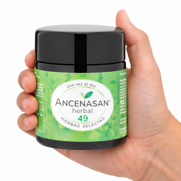 Mano sosteniendo un frasco grande de Ancensan Herbal 49 Hierbas Selectas con etiqueta verde sobre fondo blanco.