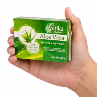 Mano sosteniendo una caja de jabón Dabur Vatika Naturals Aloe Vera con extracto de aloe vera sobre fondo blanco.
