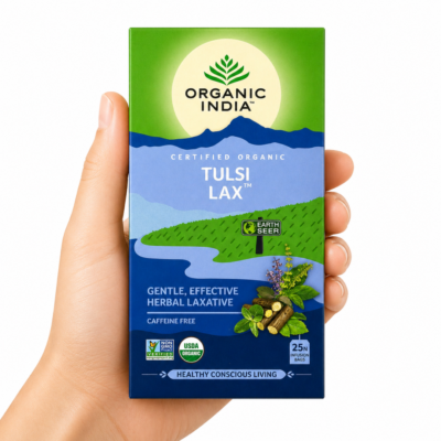 Caja de infusión Organic India Tulsi Lax sostenida por una mano neutra sobre fondo blanco, té herbal ayurvédico laxante suave sin cafeína para la digestión y el tránsito intestinal.