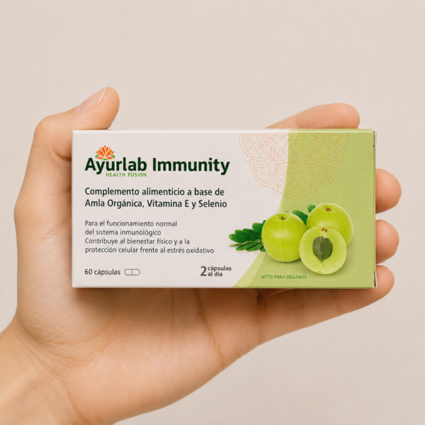 Mano neutra sosteniendo caja de Ayurlab Immunity con Amla Orgánica, Vitamina E y Selenio sobre fondo claro minimalista.