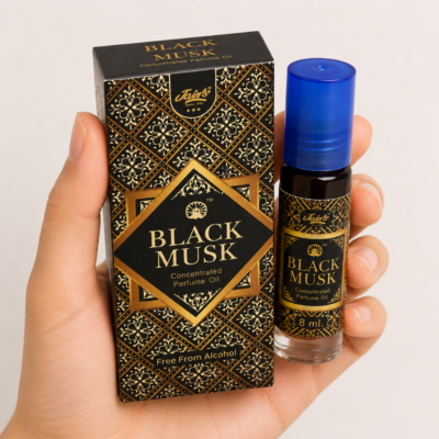 Mano neutra sosteniendo Attar Black Musk 100% natural de Jains sobre fondo beige minimalista.