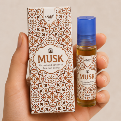 Mano neutra sosteniendo Attar Musk 100% natural de Jains con diseño geométrico beige sobre fondo minimalista.
