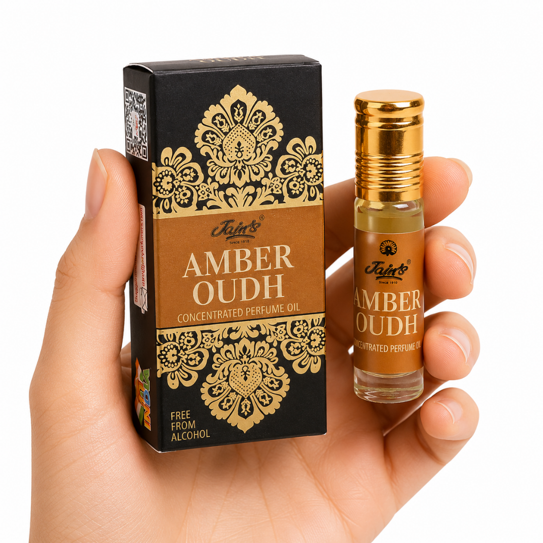 Amber Oudh Mano neutra sosteniendo Attar Amber Oudh 100% natural de Jains con diseño negro y dorado sobre fondo blanco minimalista.