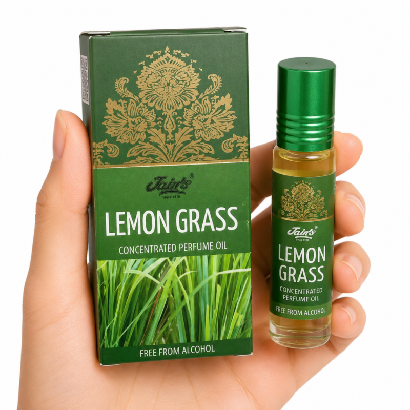 Mano neutra sosteniendo Attar Lemon Grass 100% natural de Jains con diseño verde herbal sobre fondo blanco minimalista.
