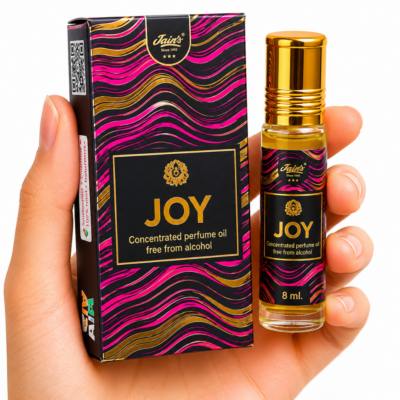 Mano neutra sosteniendo Attar Joy 100% natural de Jains con diseño negro, dorado y magenta sobre fondo blanco minimalista.