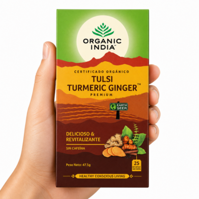 Infusión Organic India Tulsi Turmeric Ginger sostenida por una mano neutra sobre fondo blanco, té ayurvédico orgánico con cúrcuma y jengibre para bienestar digestivo e inmunológico