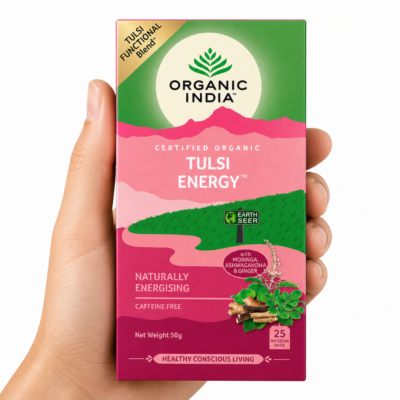 Infusión Organic India Tulsi Energy sostenida por una mano neutra sobre fondo blanco, té ayurvédico orgánico energizante con ashwagandha, moringa y jengibre
