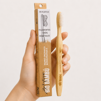 Mano neutra sosteniendo Cepillo de Dientes Bambú Bio Orgánico sobre fondo blanco minimalista.