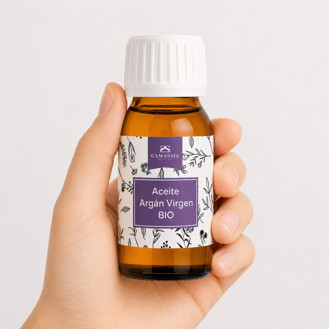 Aceite Argán Virgen Bio Mano neutra sosteniendo Aceite de Argán Virgen BIO de Camassia sobre fondo blanco minimalista.