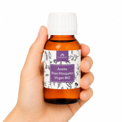 Mano neutra sosteniendo Aceite Rosa Mosqueta Virgen BIO de Camassia sobre fondo blanco minimalista.