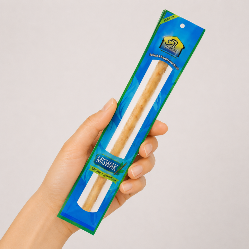 Mano neutra sosteniendo Cepillo Miswak Natural sobre fondo blanco minimalista.