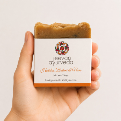 Mano neutra sosteniendo jabón natural Jeevan Ayurveda Haridra, Brahmi & Neem sobre fondo blanco minimalista.