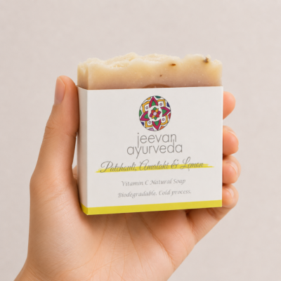 Mano neutra sosteniendo jabón natural Jeevan Ayurveda Patchouli, Amalaki & Lemon sobre fondo claro minimalista.