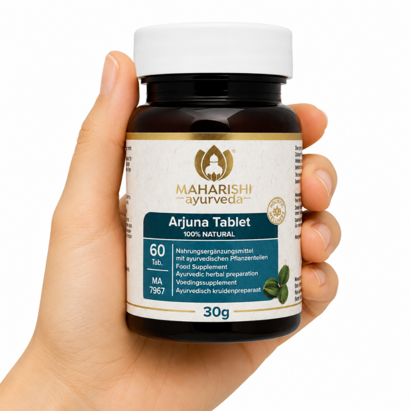 Mano sosteniendo suplemento Maharishi Ayurveda Arjuna Tablet 30g en cápsulas sobre fondo blanco.