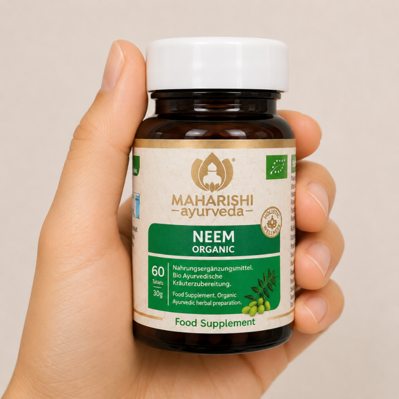Mano neutra sosteniendo suplemento Neem Organic de Maharishi Ayurveda sobre fondo claro minimalista.