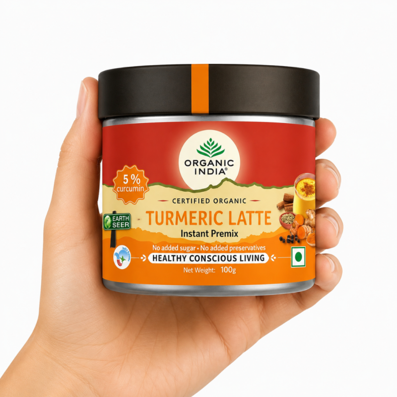 Mano sosteniendo Organic India Golden Turmeric Latte Mix 100g sobre fondo blanco
