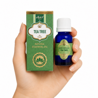 Aceite Esencial de Árbol de Té Jain's 100% natural con caja verde y frasco de vidrio azul sobre fondo blanco.