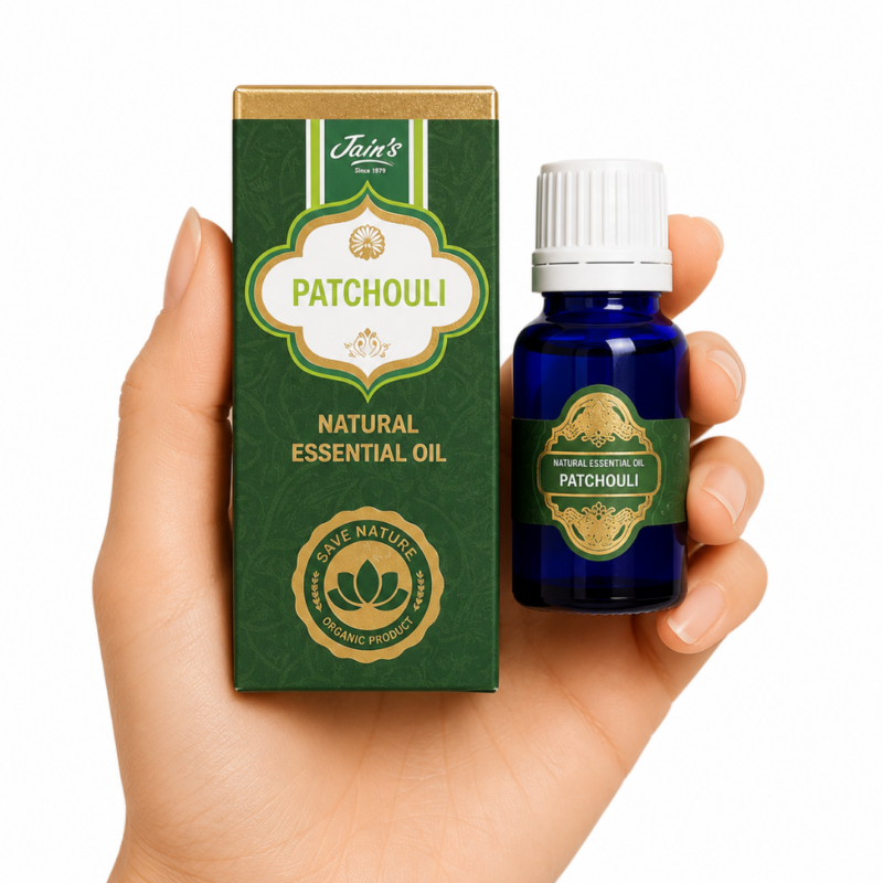 Aceite Esencial de Patchouli Jain's 100% natural con caja verde y frasco de vidrio azul sobre fondo blanco.
