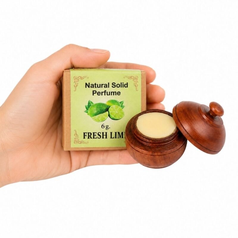 Mano sosteniendo el Perfume Sólido Fresh Lime Jains 6 g con envase de madera y caja original sobre fondo blanco.