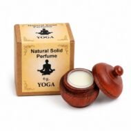 Mano sosteniendo el Perfume Sólido Yoga Jains de 6 g con envase de madera y caja original sobre fondo blanco.