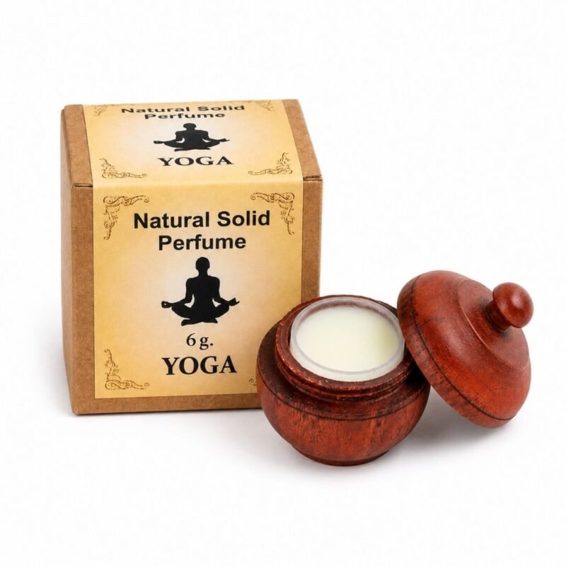 Mano sosteniendo el Perfume Sólido Yoga Jains de 6 g con envase de madera y caja original sobre fondo blanco.