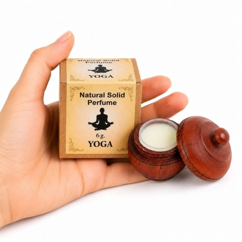 Mano sosteniendo el Perfume Sólido Yoga Jains de 6 g con envase de madera y caja original sobre fondo blanco.