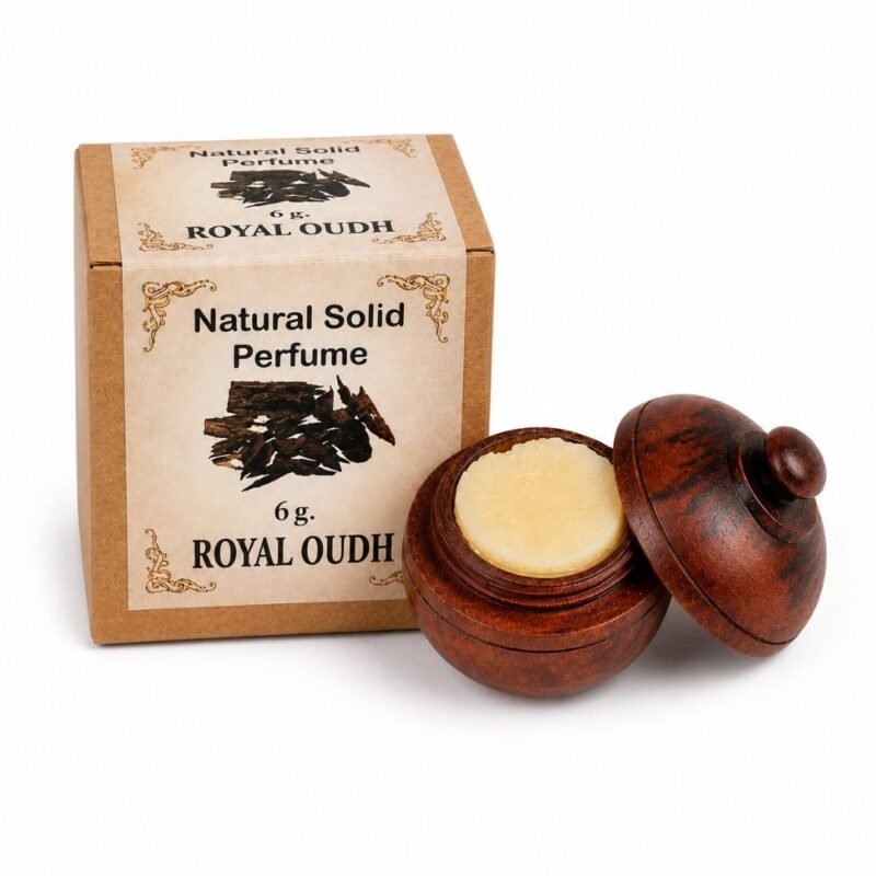 Mano sosteniendo el Perfume Sólido Royal Oudh Jains de 6 g con envase de madera y caja original sobre fondo blanco.