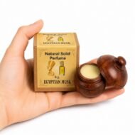 Mano sosteniendo el Perfume Sólido Egyptian Musk Jains de 6 g con envase de madera y caja original sobre fondo blanco.