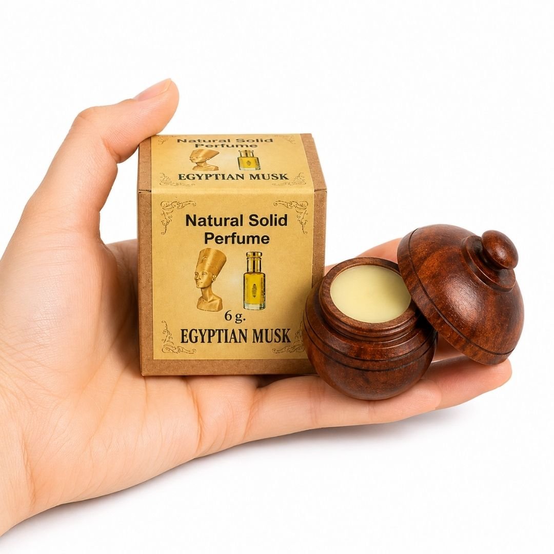 TGL 26 01 - Web - PWP-JAI-0406 - Perfume Sólido Egyptian Musk Mano sosteniendo el Perfume Sólido Egyptian Musk Jains de 6 g con envase de madera y caja original sobre fondo blanco.