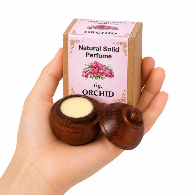 Mano sosteniendo el Perfume Sólido Natural Orchid Jains de 6 g con envase de madera y caja original sobre fondo blanco.