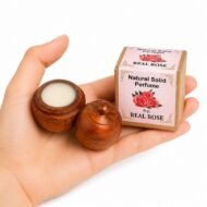Mano sosteniendo el Perfume Sólido Natural Orchid Jains de 6 g con envase de madera y caja original sobre fondo blanco.
