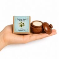Mano sosteniendo el Perfume Sólido Jasmine de Jains de 6 g con envase de madera y caja original sobre fondo blanco.
