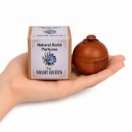 Mano sosteniendo el Perfume Sólido Night Queen de Jains de 6 g con envase de madera y caja original sobre fondo blanco.