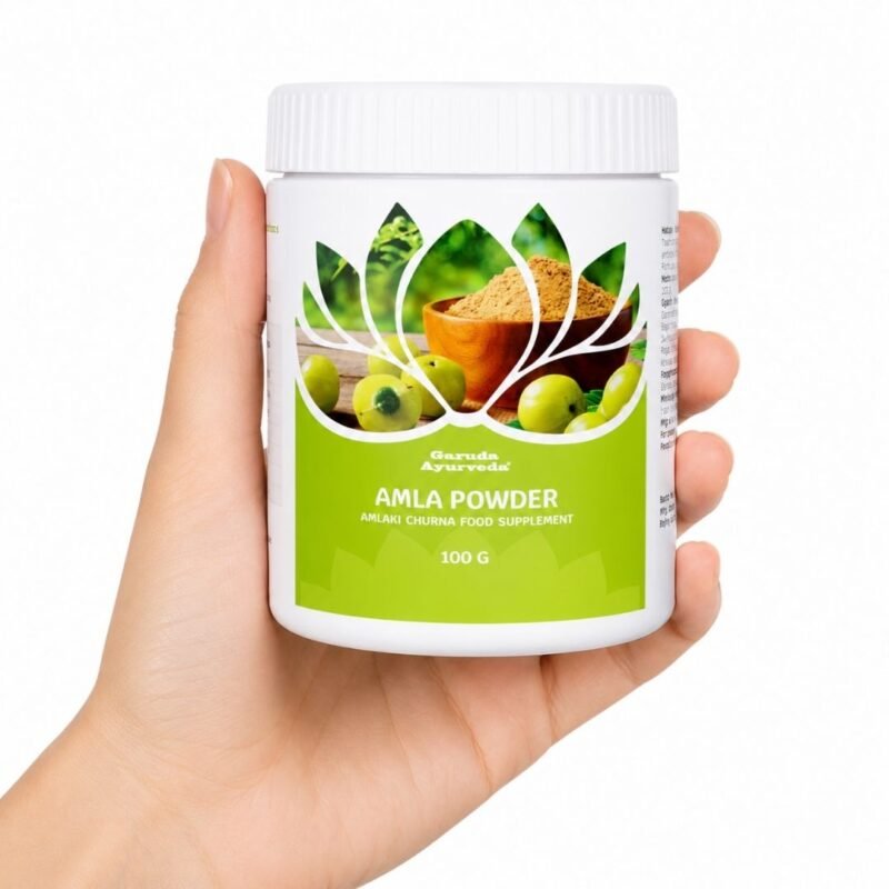 Mano sosteniendo el Amla en Polvo Garuda Ayurveda 100 g sobre fondo blanco.