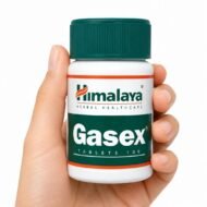 Mano sosteniendo Gasex de Himalaya, complemento alimenticio ayurvédico de 100 comprimidos sobre fondo blanco