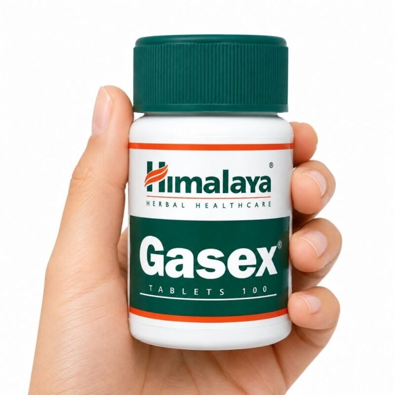 Mano sosteniendo Gasex de Himalaya, complemento alimenticio ayurvédico de 100 comprimidos sobre fondo blanco