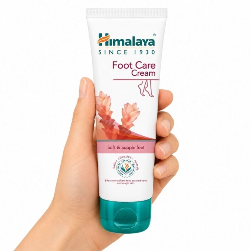 Crema para el Cuidado de Pies Foot Care Cream de Himalaya sostenida en una mano sobre fondo blanco