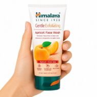 Mano sosteniendo el Limpiador Facial Exfoliante de Albaricoque de Himalaya sobre fondo blanco.