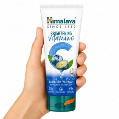 Mano sosteniendo el Limpiador Facial Vitamina C de Arándano Himalaya Brightening Vitamin C Blueberry Face Wash sobre fondo blanco.