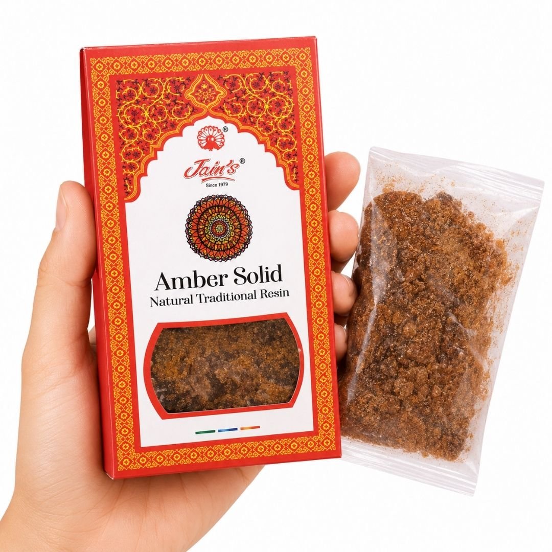 TGL 26 01 - Web - PWP-JAI-0207 - Amber Solid Mano sosteniendo Amber Solid Resin de Jain’s con caja y resina aromática tradicional sobre fondo blanco