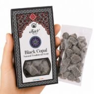 Mano sosteniendo Resina de Copal Negro Black Copal de Jain’s con caja y resina sobre fondo blanco