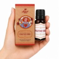 Mano sosteniendo las Gotas Mágicas Positive Vibes de Jains con frasco y caja original sobre fondo blanco.