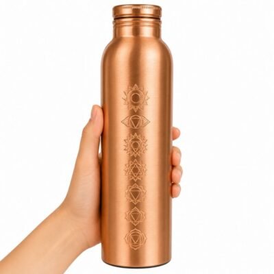 Botella de cobre con símbolos de los 7 chakras sostenida en una mano sobre fondo blanco